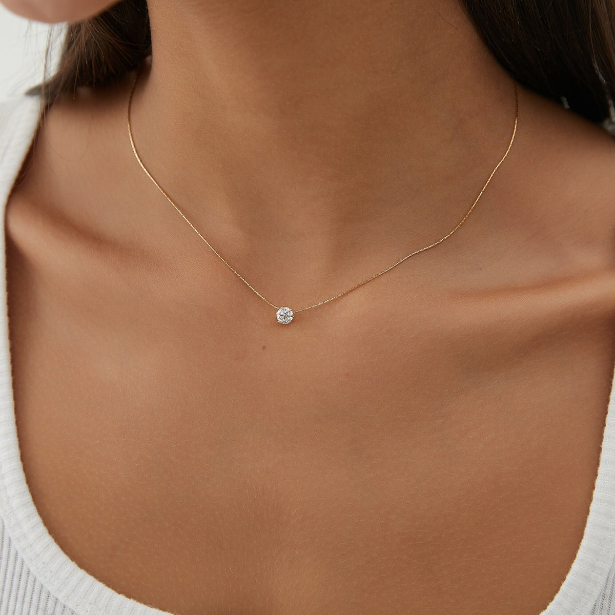 Collier pendentif zircon imitation diamant porté sur le décolleté, doré
